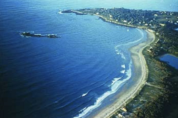 This image shows a shoreline with a peninsula sticking out and faint lines in the waves showing refraction